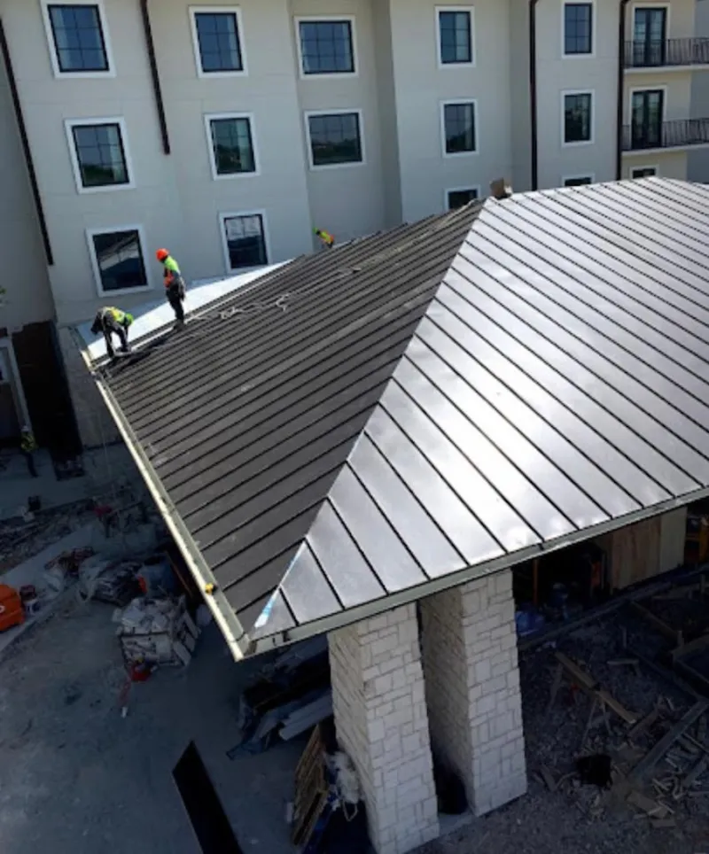 Crew installing standing seam metal roof panels on a commercial project in Sanger